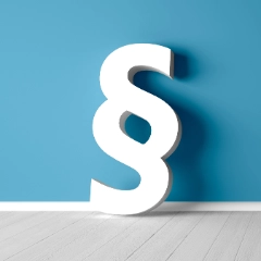 Ein weißes Paragraphensymbol steht vor einer blauen Wand